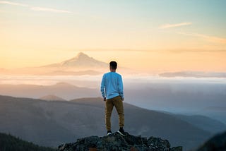 Person standing on top of a mountain looking out over the range