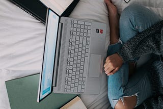 A girl is sitting on the bed and studing/learning/working.