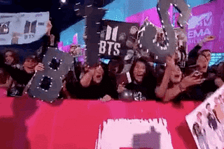 BTS fans cheering and waving signs at a 2017 awards show.