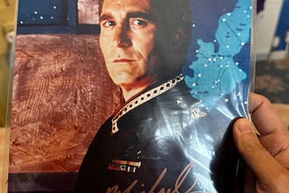 Photo held in right hand. Photo of white man with dark hair in a militaristic dress uniform. Signature on photo in gold ink. Reads “Michael O’Hare.”