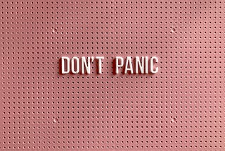 Pink pinboard with the words “Don’t Panic” pinned to it