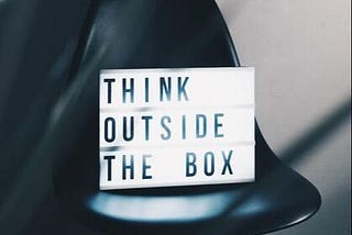 Lightbox with the words ‘think outside the box’ sits on top of a black chair