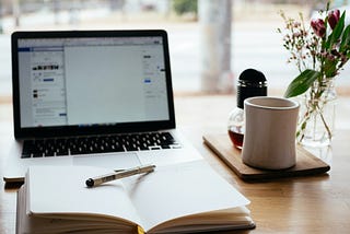 An open laptop and a diary on a desk