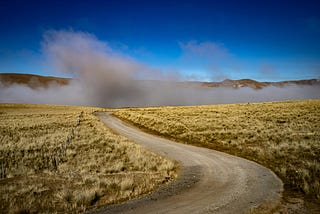 a long dusty road under a brilliant blue sky