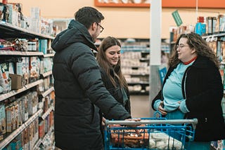 Three people chatting in a grocery store aisle.