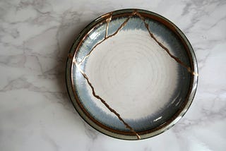 A picture of a cracked ceramic bowl that has been repaired with gold. Used to depict the art of perfect imperfection after being patched up with gold to make an even more beautiful piece.