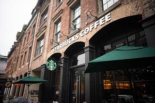 outside a starbucks coffee shop in an older building with green umbrellas