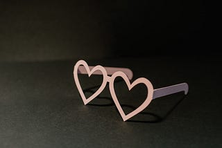 Pink heart shaped glasses on black background