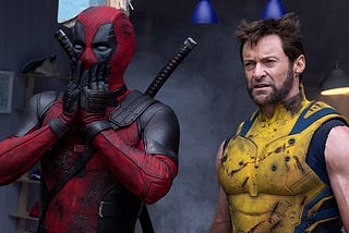 Deadpool with a look of shock on his face stands next to Wolverine who has more of a look of bewilderment in this still from Deadpool and Wolverine.
