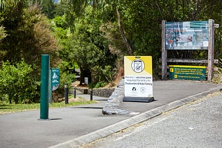 A yellow road sign saying Kia Ora — Vaccine Pass Required For Entry