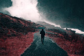 Man walking in rain with umbrella on a loneley road