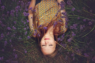 Woman laying on a bed of heather with her eyes closed.
