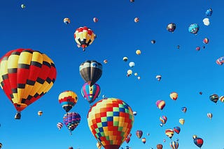 Many hot air balloons in a blue sky