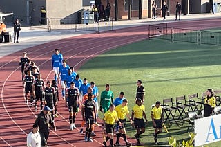 The teams walk out from the locker rooms onto the field.