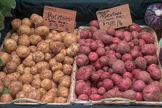 Two bins of potatoes, red and white, waiting to be roasted.