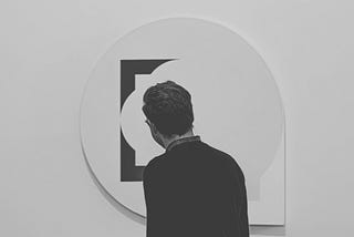 The back of someon’es head looking at a piece of art, round and square and balloon shapes