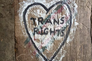 Trans Rights in a heart painted on what looks like a telephone poll but might be a bar table.