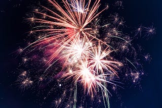 Fireworks explode in the center of the frame. The author has used this image to show the ending of one year and the beginning of new one.