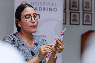 A doctor holds a needle and syringe.