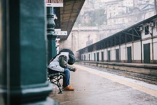 A man sitting on a bench with his head down