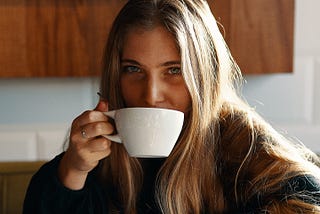 An everyday woman drinks from her mug of coffee