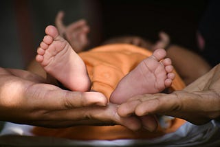 A man holds a baby’s feet in his hands