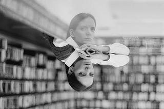 Grayscale photo of woman in a library with reflection