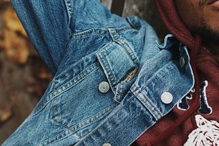 Middle aged man in blue denim jacket, and brown sweaters lies down closing his eyes reminiscing peace of mind and solitude.