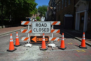 Street with barricade in the middle with sign saying “Road Closed”.