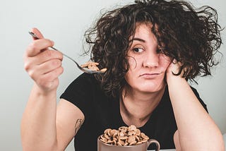 A woman sits eating cereal