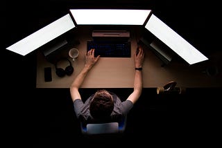 Photo of a man working on a computer with multiple monitors.