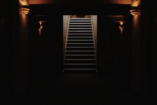 Stairway leading up from the darkness. Photo by Ginevra Austine on Unsplash