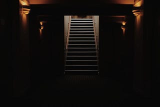 Stairway leading up from the darkness. Photo by Ginevra Austine on Unsplash