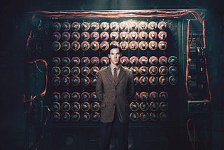 A movie scene shot of actor Benedict Cumberbatch as Alan Turing standing in front of the Imitation Game movie rendition.