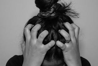 Woman with her head in her hands. She is stressed.