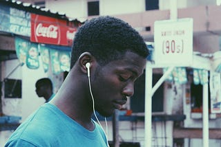 A young man in an urban background quietly looks at the ground while walking