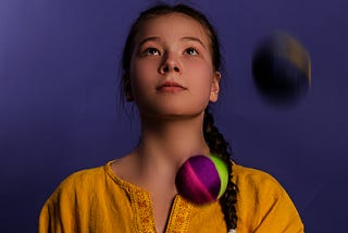 A professional woman is juggling balls, symbolizing her commitments to work, writing, and self-care