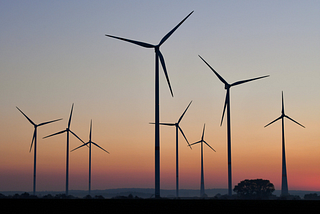 A rad view of wind turbines against a sunset