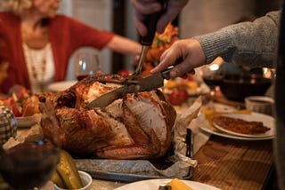 Turkey being carved on a table set for a Thanksgiving meal