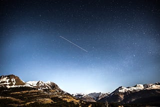 A shooting star over mountains.