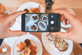 A person holds a camera phone on a Western meal about to take a photo