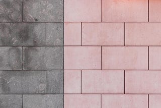 A brick wall, half grey, half pink.