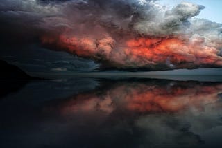 A storm cloud reflected in the still surface of a lake