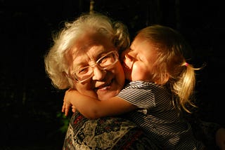 Old lady getting cuddled by a child.