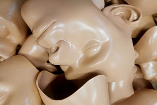 Beige plastic human face masks lying in a pile