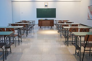 An empty classroom with white walls and tile floors.