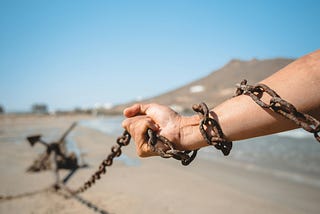 A hand in chains, pulling heavy chain tied to something far behind, dragging along the ground. Used to depict how unforgiveness is like carrying around burdens that you can simply lay down.