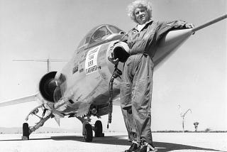 Black and white Photo of Jacqueline Cochran in flying uniform standing in front of Lockheed F-104G Super Starfighter plane on runway. Posted on mickey markoff 2024 article on women in aviation; credit — US San Diego Air & Space Museum