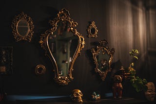 A wall is covered with an assortment of different sized gold framed mirrors.