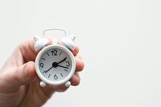 A hand holding a clock.